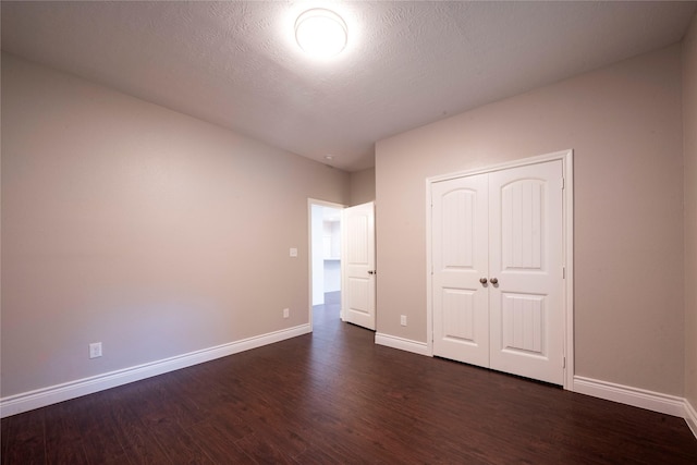 unfurnished bedroom featuring dark hardwood / wood-style flooring, a closet, and a textured ceiling