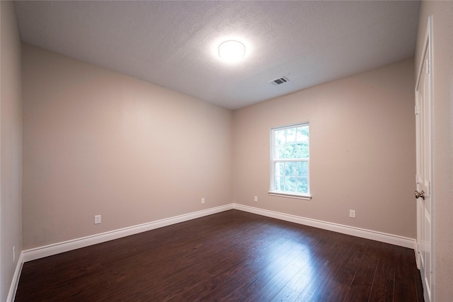 empty room featuring dark wood-type flooring and a textured ceiling