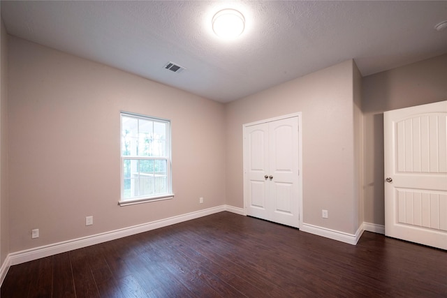 unfurnished bedroom with a closet, dark hardwood / wood-style floors, and a textured ceiling