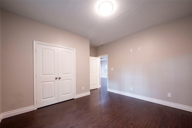 unfurnished bedroom featuring dark wood-type flooring, a textured ceiling, and a closet