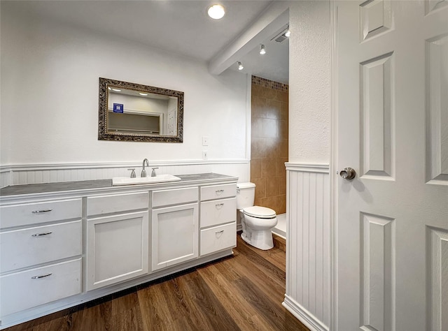 bathroom featuring vanity, wood-type flooring, beamed ceiling, and toilet