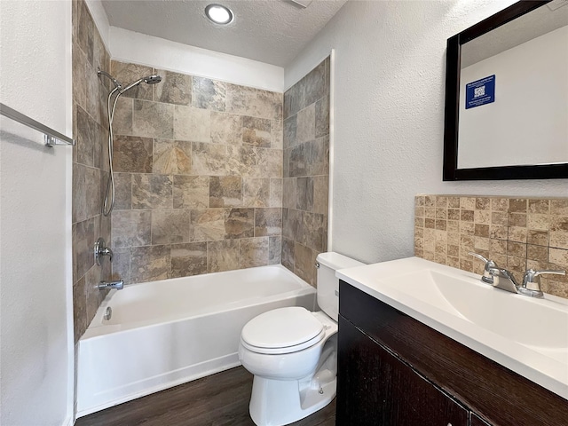 full bathroom featuring tasteful backsplash, tiled shower / bath combo, hardwood / wood-style flooring, toilet, and a textured ceiling