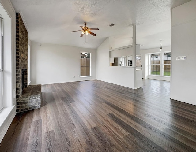 unfurnished living room featuring a brick fireplace, a textured ceiling, and dark hardwood / wood-style flooring