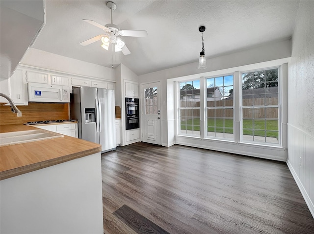 kitchen with lofted ceiling, stainless steel fridge with ice dispenser, hanging light fixtures, dark hardwood / wood-style floors, and white cabinets