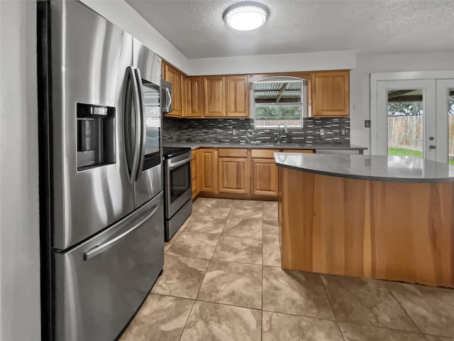5210 3rd St, Danbury, TX 77534 - kitchen with appliances with stainless steel finishes, a textured ceiling, decorative backsplash, a sink, and dark countertops