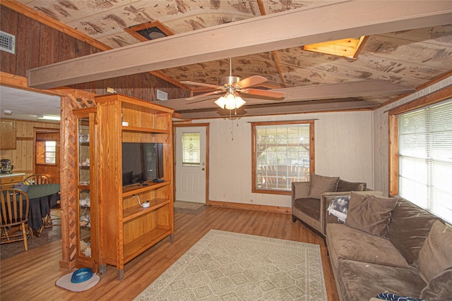 living room featuring vaulted ceiling, wood walls, light hardwood / wood-style floors, and a wealth of natural light