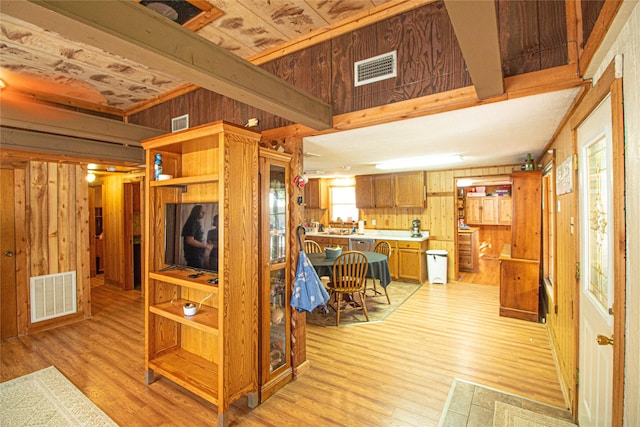 interior space featuring wooden walls, beam ceiling, and light wood-type flooring