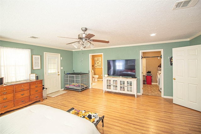 bedroom featuring hardwood / wood-style flooring, a walk in closet, crown molding, and a textured ceiling