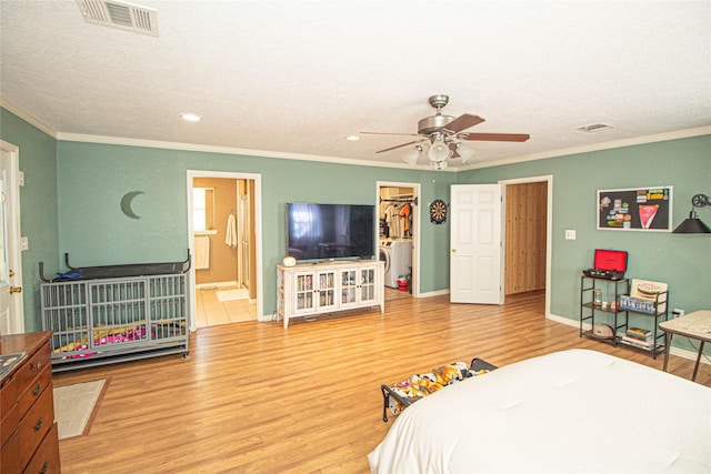 bedroom featuring a walk in closet, ornamental molding, and hardwood / wood-style floors