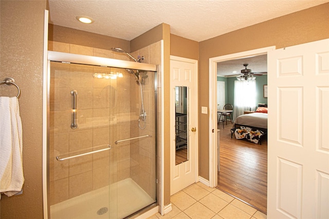 bathroom with tile patterned flooring, ceiling fan, an enclosed shower, and a textured ceiling