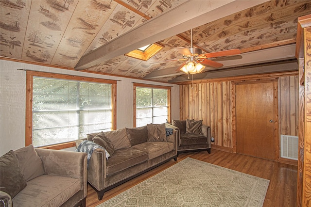 living room featuring vaulted ceiling with skylight, wood walls, dark hardwood / wood-style flooring, ceiling fan, and wood ceiling