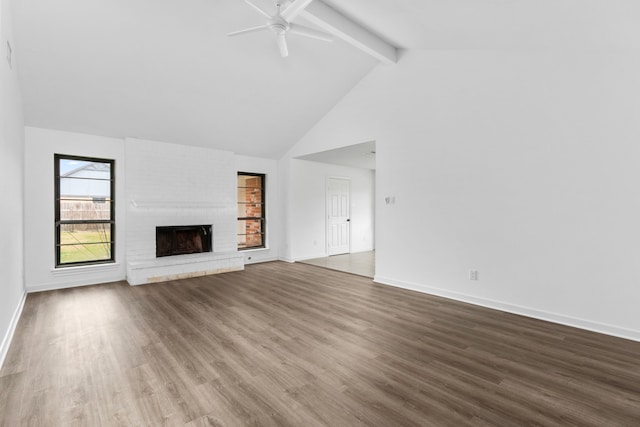 unfurnished living room with hardwood / wood-style flooring, ceiling fan, high vaulted ceiling, a brick fireplace, and beamed ceiling