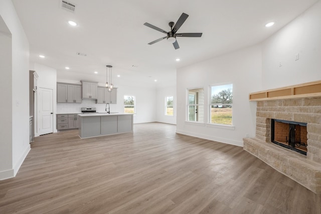 4974 County Road 128, Iola, TX 77861 - unfurnished living room featuring ceiling fan, sink, a stone fireplace, and light hardwood / wood-style floors