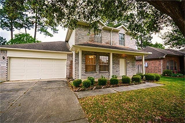 view of front of home with a garage, covered porch, and a front lawn