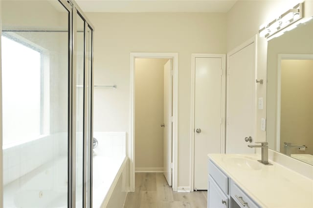 bathroom with hardwood / wood-style flooring, vanity, and plus walk in shower