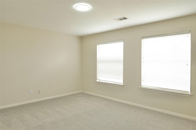 spare room featuring light colored carpet and a healthy amount of sunlight