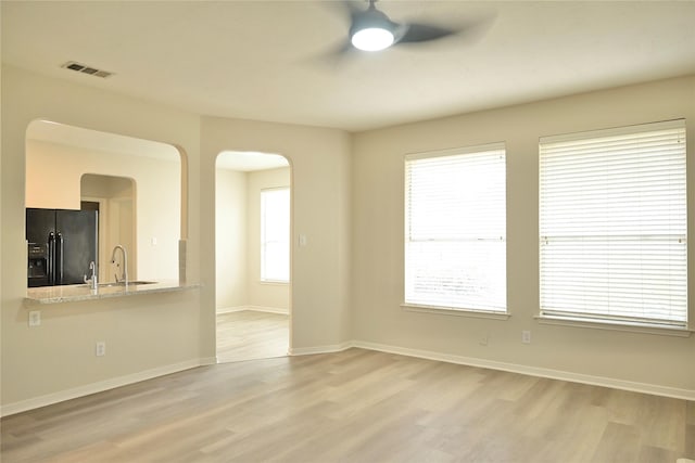 unfurnished room featuring sink, ceiling fan, and light hardwood / wood-style flooring