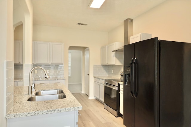 kitchen featuring stainless steel electric range oven, white cabinetry, sink, light stone counters, and black fridge