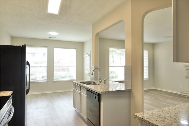 kitchen featuring a healthy amount of sunlight, light stone countertops, sink, and black appliances