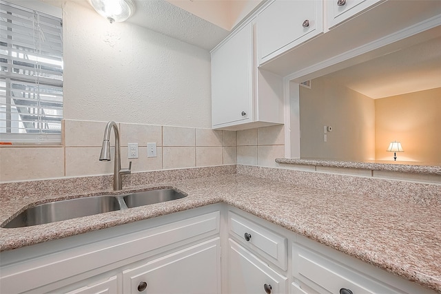 kitchen featuring tasteful backsplash, sink, and white cabinets