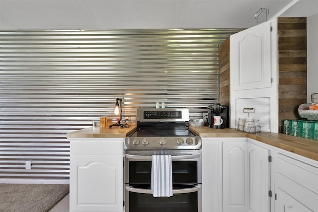 kitchen with white cabinetry, double oven range, wooden walls, and kitchen peninsula