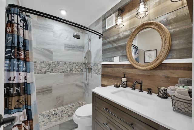 bathroom with vanity, curtained shower, wooden walls, and toilet