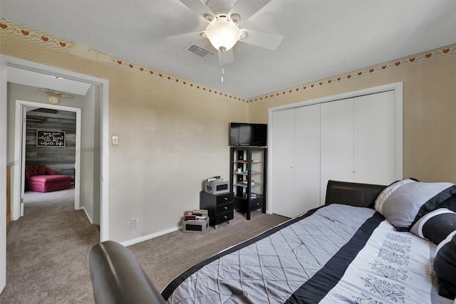 bedroom with ceiling fan, carpet flooring, a closet, and a textured ceiling