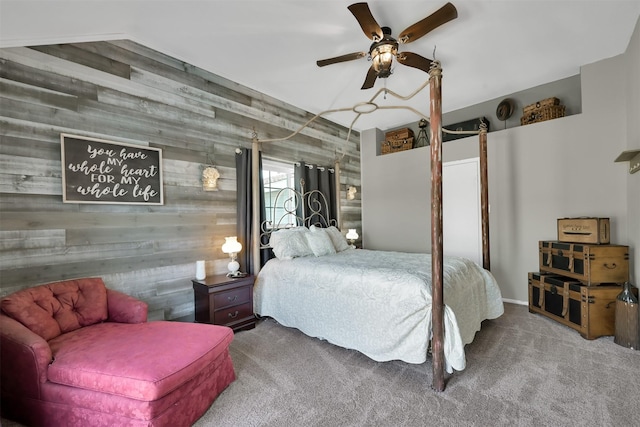 bedroom with carpet flooring, ceiling fan, and wood walls