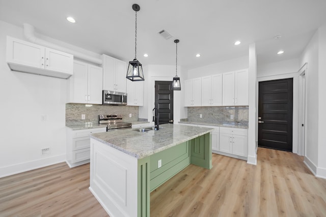 kitchen with sink, light stone counters, an island with sink, stainless steel appliances, and white cabinets