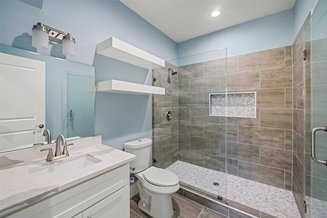 bathroom with vanity, toilet, and a shower with door