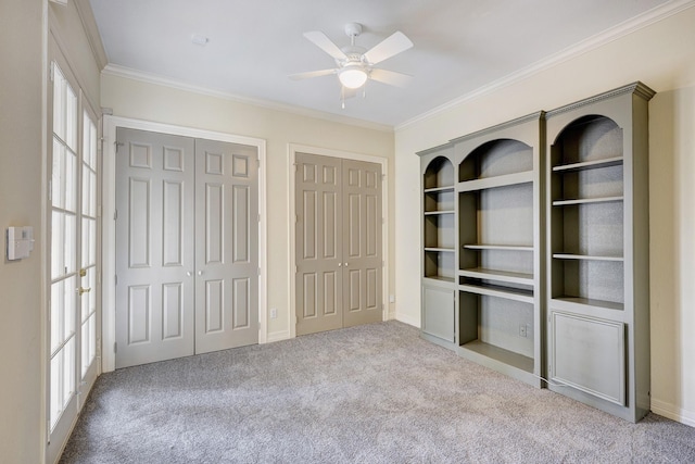 unfurnished bedroom with ceiling fan, ornamental molding, light carpet, and two closets