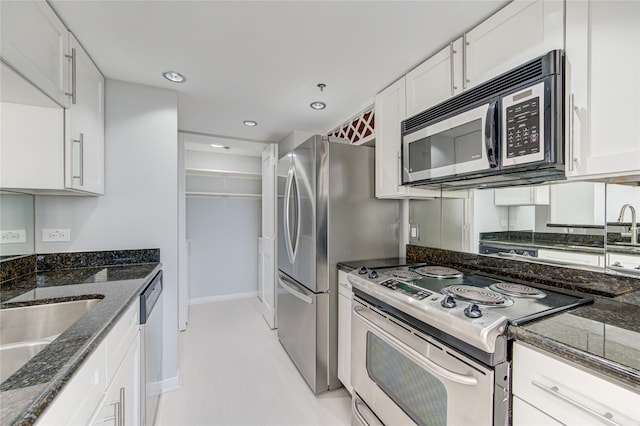 kitchen featuring appliances with stainless steel finishes, sink, white cabinets, and dark stone counters