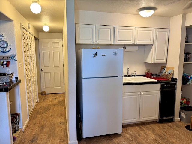 kitchen with white refrigerator, sink, white cabinets, and light hardwood / wood-style flooring