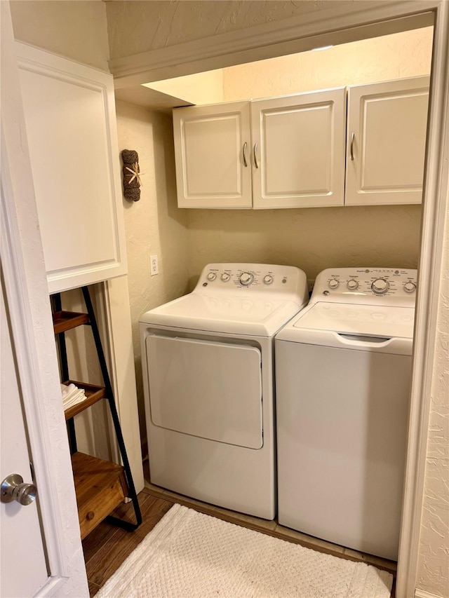 washroom featuring hardwood / wood-style flooring, cabinets, and washing machine and clothes dryer