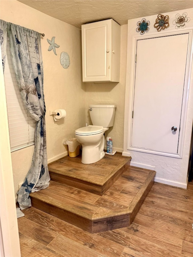 bathroom featuring wood-type flooring, a textured ceiling, and toilet