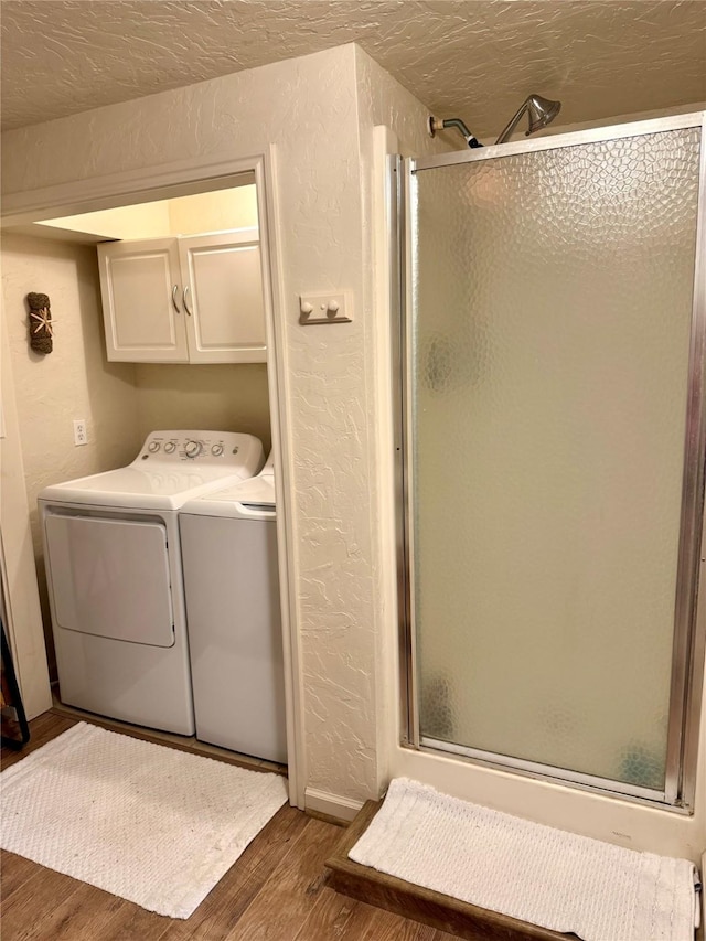 clothes washing area with cabinets, dark hardwood / wood-style floors, washer and dryer, and a textured ceiling