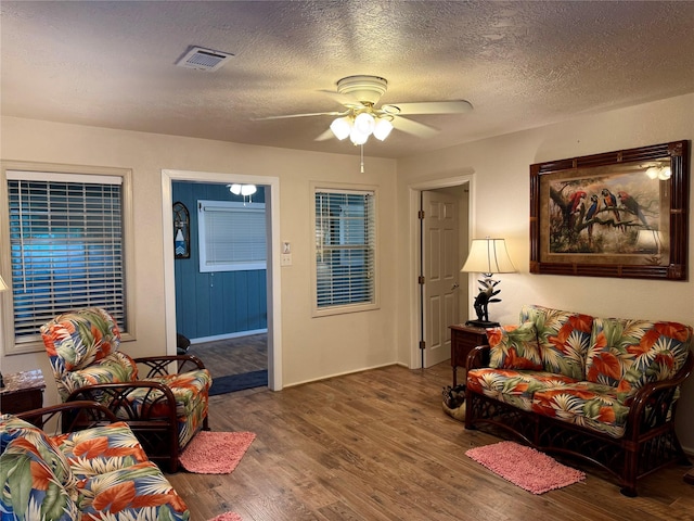 living room with ceiling fan, dark wood-type flooring, and a textured ceiling