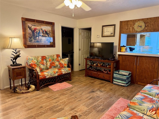 living room featuring ceiling fan, a textured ceiling, and light hardwood / wood-style flooring