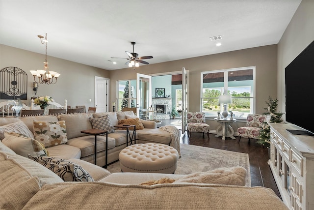 living room with dark wood-type flooring and ceiling fan with notable chandelier