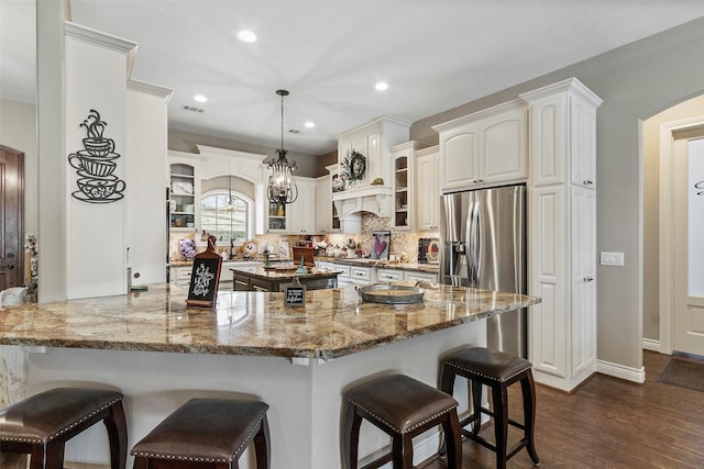 kitchen with pendant lighting, white cabinetry, light stone countertops, dark hardwood / wood-style flooring, and kitchen peninsula