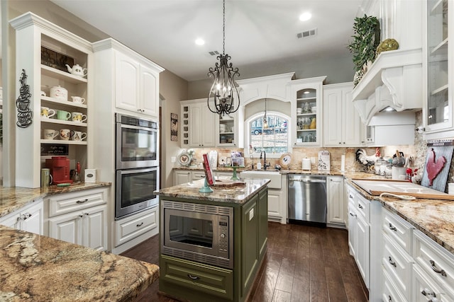 kitchen with a kitchen island, white cabinetry, hanging light fixtures, stainless steel appliances, and dark wood-type flooring