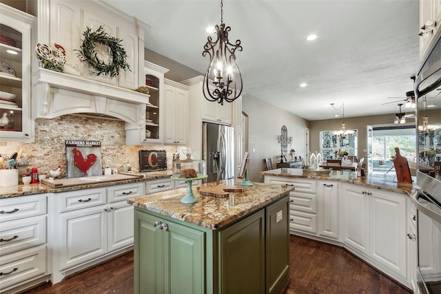 kitchen with white cabinetry, light stone counters, hanging light fixtures, appliances with stainless steel finishes, and a kitchen island