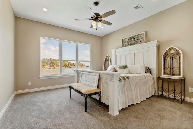 bedroom featuring light carpet, ceiling fan, and a water view