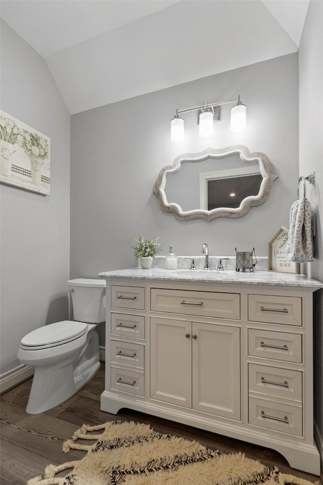 bathroom featuring vaulted ceiling, wood-type flooring, vanity, and toilet