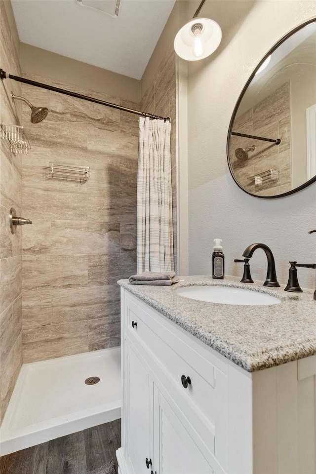 bathroom with walk in shower, vanity, and wood-type flooring