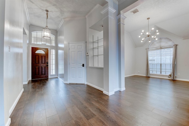 entryway featuring crown molding, high vaulted ceiling, dark hardwood / wood-style floors, a notable chandelier, and decorative columns