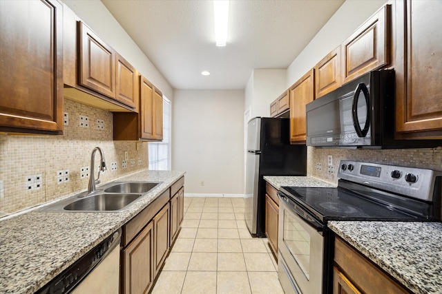 kitchen featuring sink, decorative backsplash, light tile patterned floors, stainless steel appliances, and light stone countertops