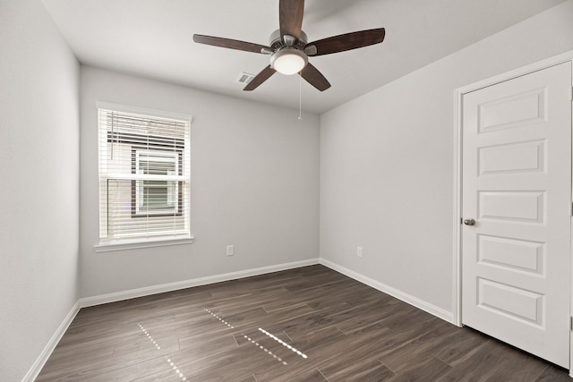 unfurnished room featuring dark wood-type flooring, a ceiling fan, visible vents, and baseboards