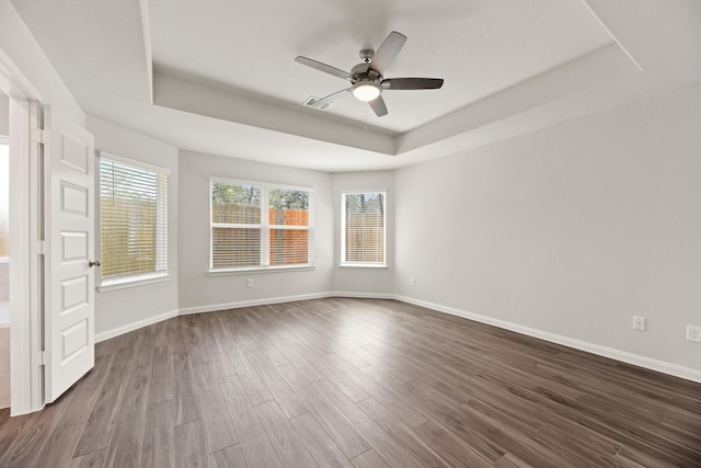 unfurnished room featuring visible vents, baseboards, a raised ceiling, and dark wood-style flooring