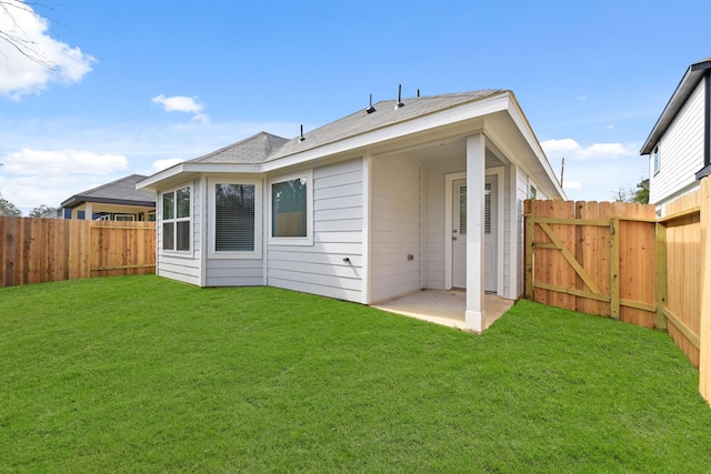 rear view of house with a lawn, a patio area, a fenced backyard, and a gate